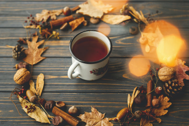 乡村金属杯，茶和秋天的花环由树叶，浆果，橡子和松果在深色的木头背景。你好下降!舒适的秋天的图片图片下载
