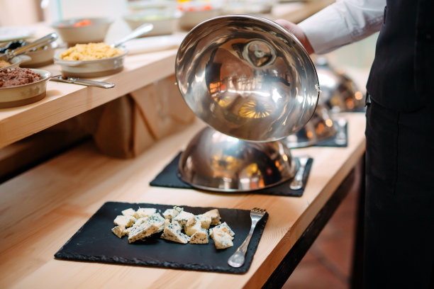 在带帽的金属碗上切奶酪。酒店或餐厅早餐。图片下载