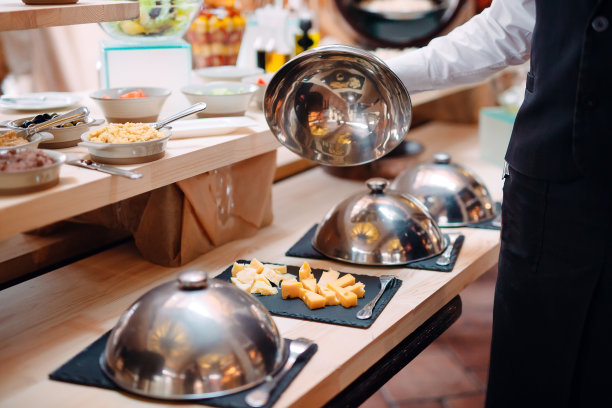 在带帽的金属碗上切奶酪。酒店或餐厅早餐。图片下载