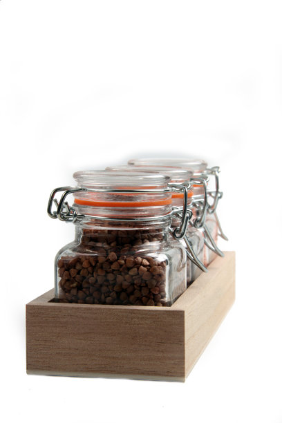 三个装谷物的玻璃罐子放在一个木制的容器里，孤立在白色的背景上图片下载