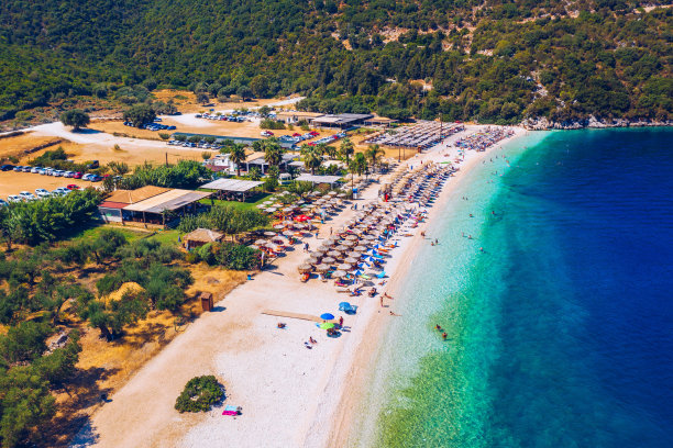 暑假的概念。从上面看，一个令人惊叹的海滩与海滩伞和绿松石清澈的水鸟瞰图。顶视图在阳光躺椅下的一把伞在沙滩上图片下载