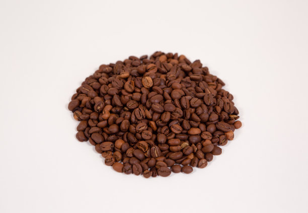 在一个白色的背景上，在一个均匀的堆孤立烤咖啡豆。图片下载