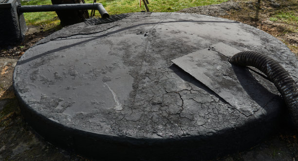 旧的地下原油储罐，上面覆盖着一层黑色的重油和沥青。图片下载