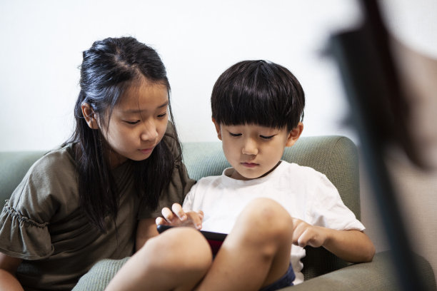 孩子们坐在沙发上玩着平板电脑图片下载