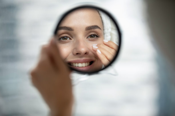 近距离微笑美丽的女人看着小圆镜图片下载