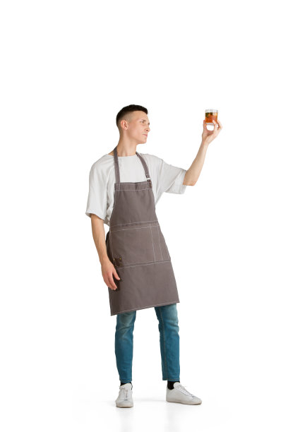 孤立的肖像，一个年轻的白人咖啡师或调酒师在棕色围裙微笑图片下载