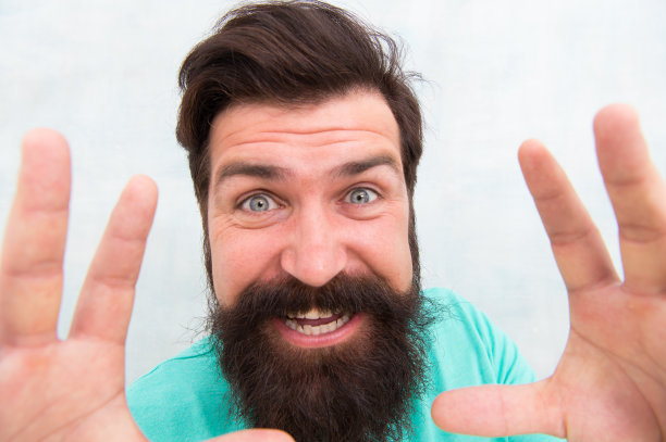 我会抓住你的。时髦的胡子和胡子护理。快乐的脸。胡须时尚和理发师。近距离观看英俊的微笑男子。男子气概的概念。留着时髦胡子的男人灰色背景图片下载