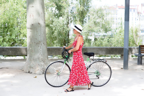 一个女人在镇上推着自行车走着图片下载