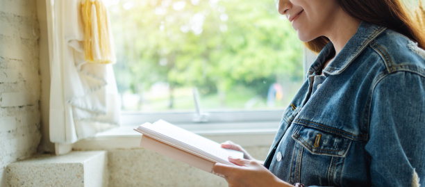 一个美丽的亚洲女人坐在家里看书图片下载