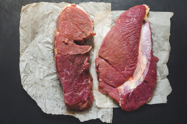 黑色背景上的生牛肉块和包装纸。图片下载