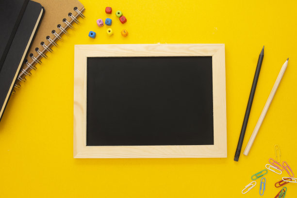 黄色背景上的粉笔板和学习用品。回归学校理念，平躺在家上学。图片下载