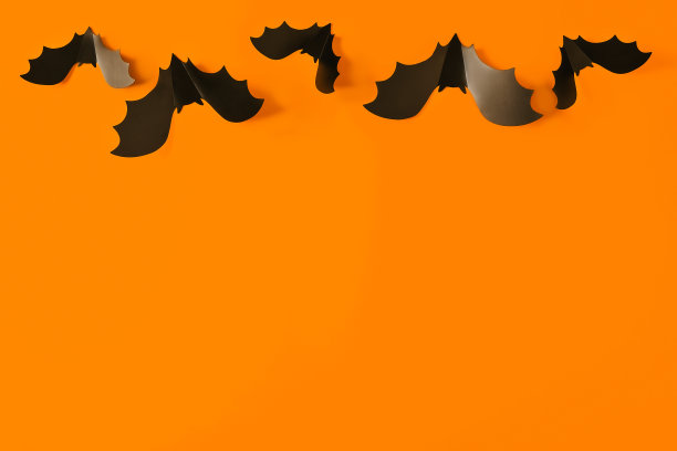 卡通万圣节背景黑色蝙蝠在橙色的背景。明亮的假日背景为您的设计。黑暗而阴沉的背景。图片下载