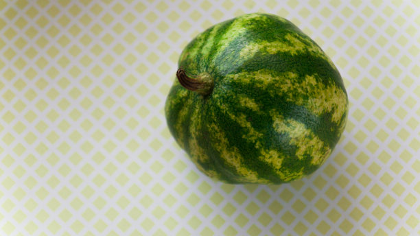 黄色斑纹背景上的绿色小西瓜。甜可口的水果。在秋天收获。有选择性的重点。图片下载