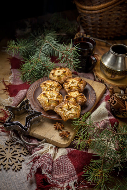 新年糕点。简单的纸杯蛋糕配上苹果。静物——自制的松饼放在盘子里。木桌上放着甜点。圣诞甜食。星形的松饼。云杉分支。Cezve图片下载