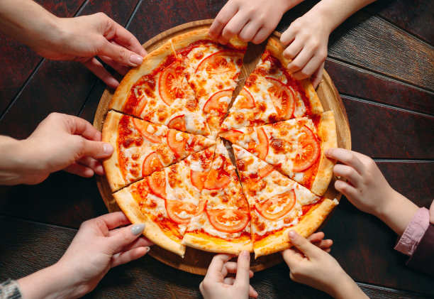 手从木桌上拿起披萨片，近景。图片下载