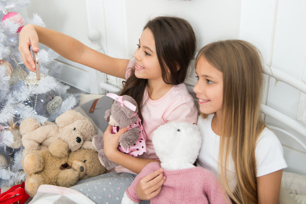 在社交媒体上分享图片。快乐的孩子与手机。用智能手机自拍圣诞和新年。小女孩在床上使用电话。圣诞快乐，恭贺新禧图片下载