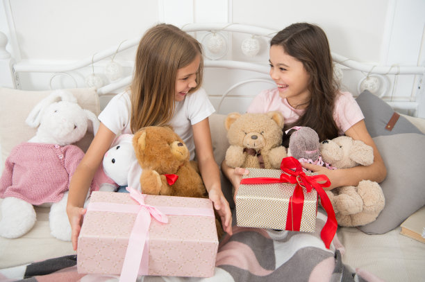 圣诞节早晨的概念。孩子们在圣诞节早上醒来。让我们打开圣诞礼物。姐妹们最好的朋友带着玩具和礼品盒在床上放松。圣诞快乐，快乐的孩子们图片下载