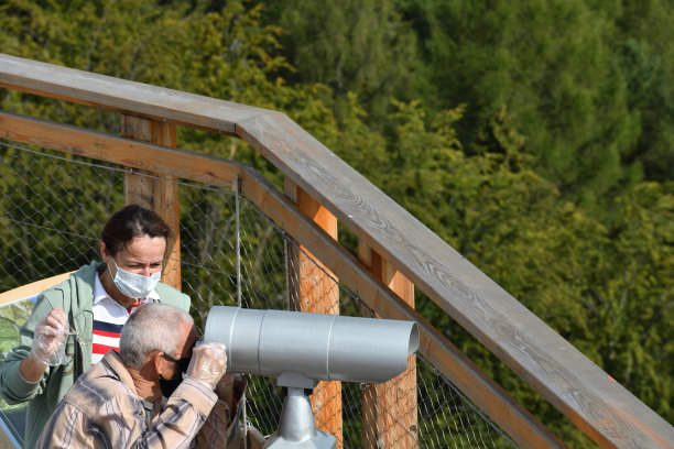 一男一女通过塔上的远程观光望远镜望着树林图片下载