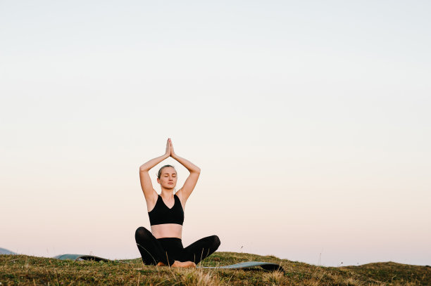 小女孩在美丽的风景中做瑜伽健身运动。早晨日出，合十莲花姿势。冥想。一个女人在山上练瑜伽。在大自然中放松。图片下载