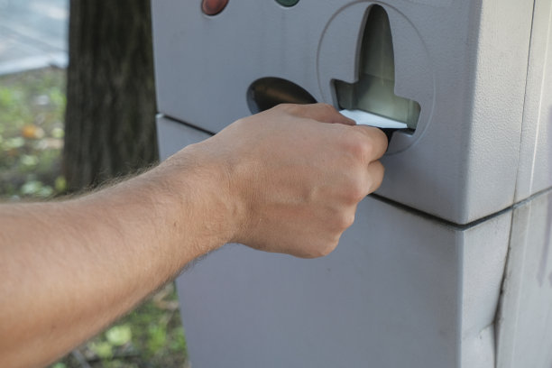 从停车机/自动售货机领取停车支票/罚单的人。手的特写。交通工具。城市基础设施图片下载