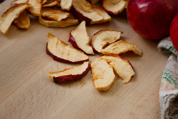干苹果片和红苹果放在桌子上。前视图。图片下载