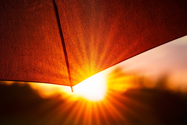 黑色的伞和橙色的阳光在背景，美丽朦胧的夕阳光透过伞打开图片下载