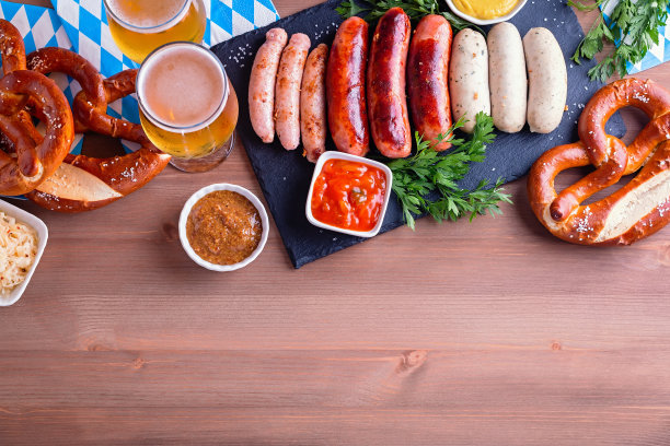 啤酒节餐桌上的传统食物。烤香肠，椒盐卷饼，啤酒，酸菜，芥末木背景，俯视图，拷贝空间，网络横幅图片下载