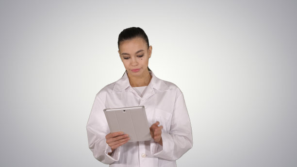 医生在渐变背景下行走时使用平板电脑图片下载