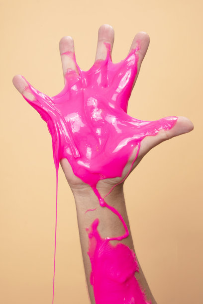 手显示五号与霓虹粉色黏液玩具在橙色波普艺术背景。图片下载