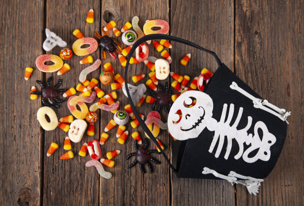 万圣节杰克提灯桶底部的糖果溢出棕色的木头。图片下载