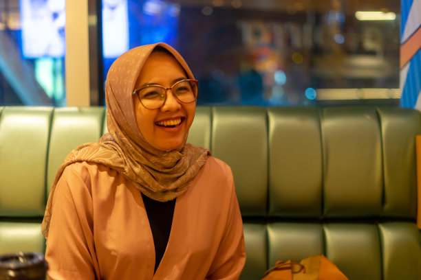 亚洲千禧一代商业女性在餐厅里用社交距离标志开怀大笑图片下载