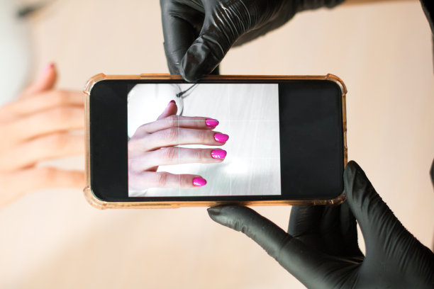 戴着黑手套的美甲师正在用智能手机拍摄美甲照片图片下载