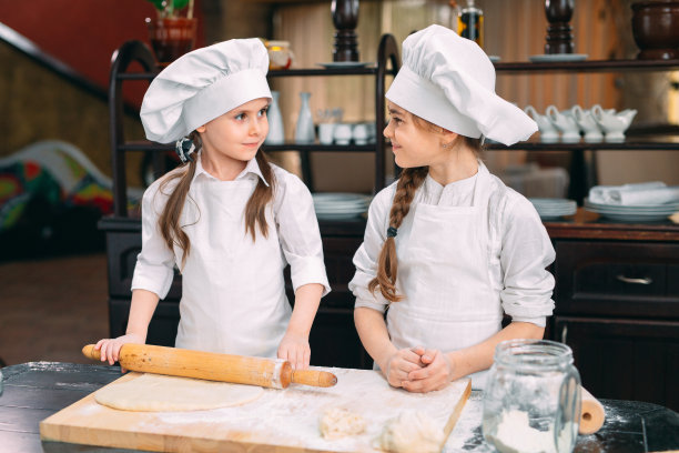 有趣的女孩，孩子们正在厨房里准备生面团。图片下载