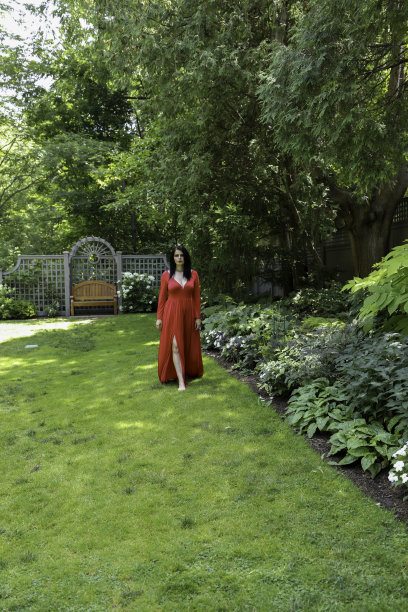 有魅力的女人穿着红色长裙走过花园图片下载