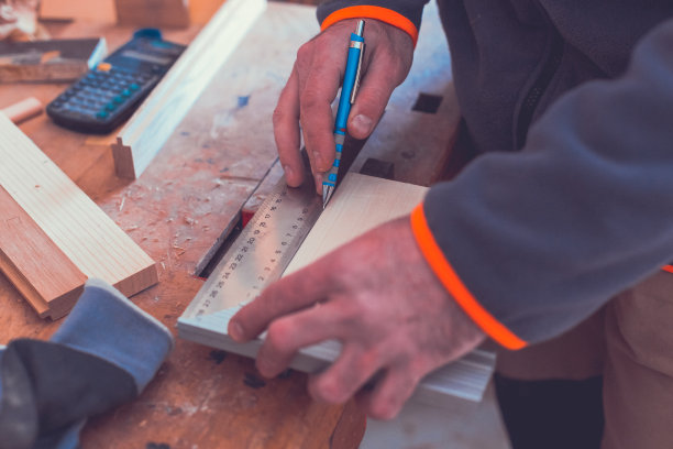 男性木匠用尺子和铅笔在木地板上画上标记的特写。DIY的概念。图片下载