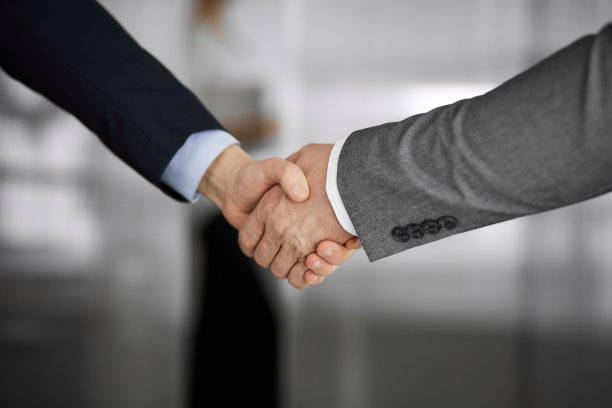 商务人士穿着西装站着握手，特写。商务沟通的概念。握手和营销图片下载