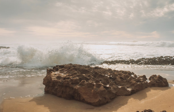 俯瞰大西洋的沙滩，海浪撞击岩石，使溅起的水和白色的空气泡沫泡沫在日落。图片下载