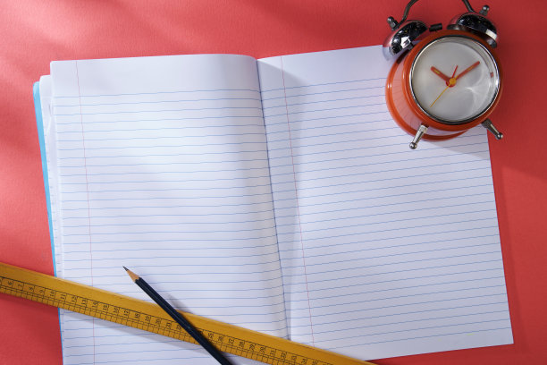 空白笔记本闹钟和钢笔红色背景。业务概念图片下载