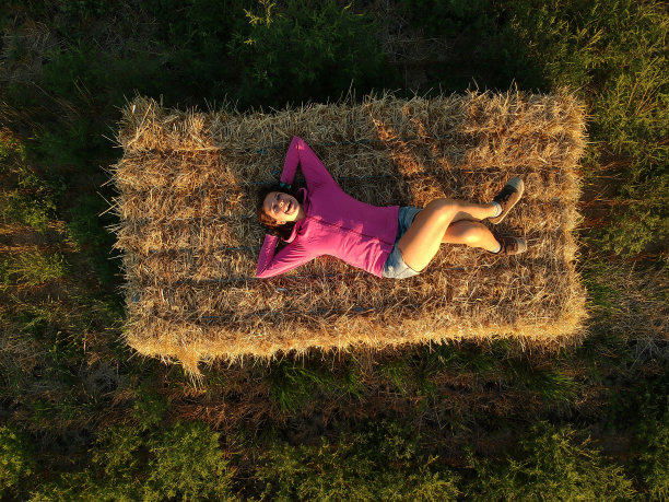 一个穿着便服的年轻女子躺在一捆稻草上。图片下载
