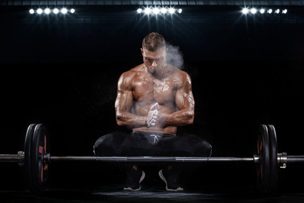 强壮肌肉健美运动员的照片，在黑色的背景上举起杠铃的肌肉。健身能量概念。图片下载