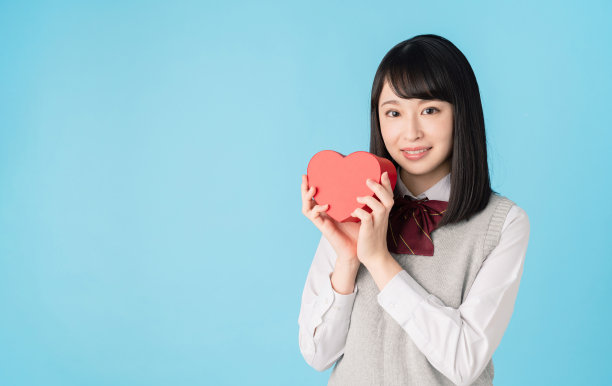 亚洲女学生拿着一个心形盒子。图片下载
