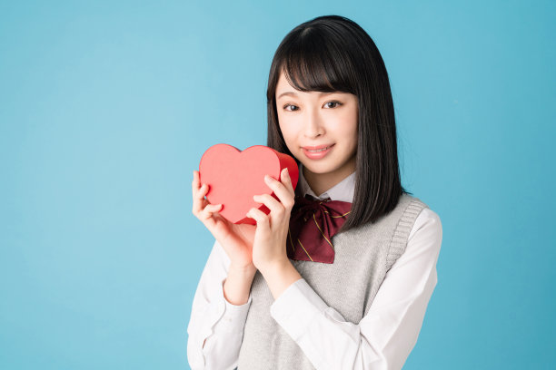 亚洲女学生拿着一个心形盒子。图片下载