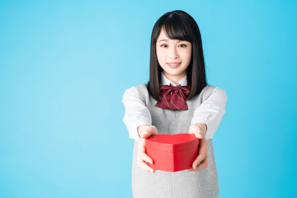 亚洲女学生送心形盒子。图片下载