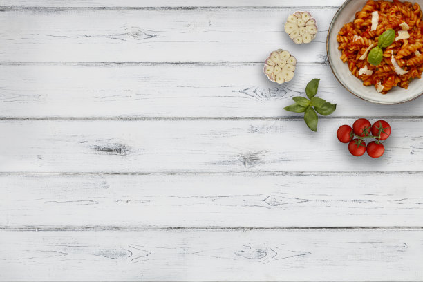 一碗美味的番茄意面放在一个质朴的碗里，配上一根罗勒枝，配上配料，在白色的木制背景上，有复制空间图片下载