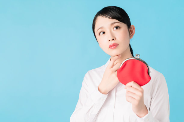 年轻的亚洲女孩拿着一个硬币钱包。图片下载