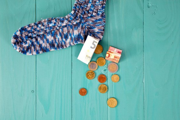 把钱放在袜子里。储蓄的袜子。硬币从羊毛袜子溢出图片下载