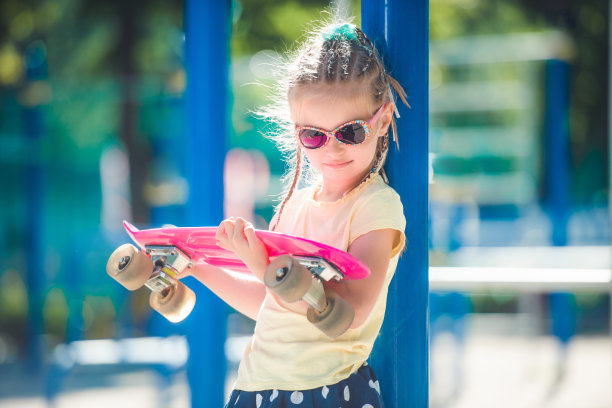 小女孩在操场上拿着粉红色的滑板图片下载
