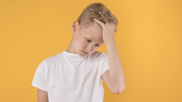 一个不高兴的男孩抓着头向下看图片下载