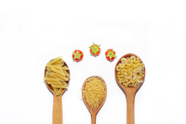 白色背景上的木勺里有几种通心粉。木勺子上的通心粉。白色背景上的通心粉。关于意大利面选择的文章。做这道菜的材料。副本的空间。孤立的背景。食物供应。圣女果图片下载