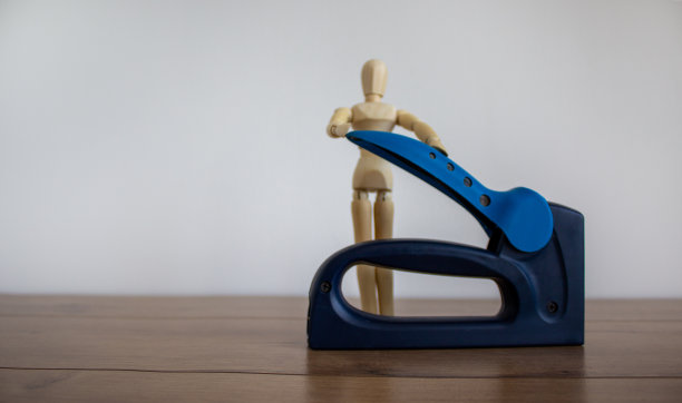 木桌上的订书机。木制的人类模型。美丽的白色背景。副本的空间。图片下载